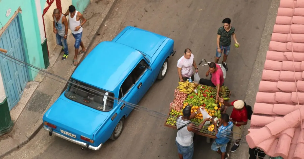 A street in Havana with people purchasing from a fruit stall