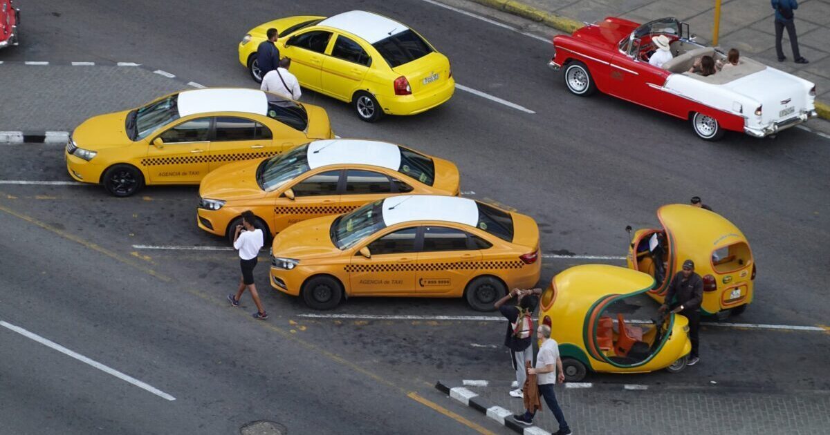 Yellow taxis and bicycle taxis parked in bays on the road