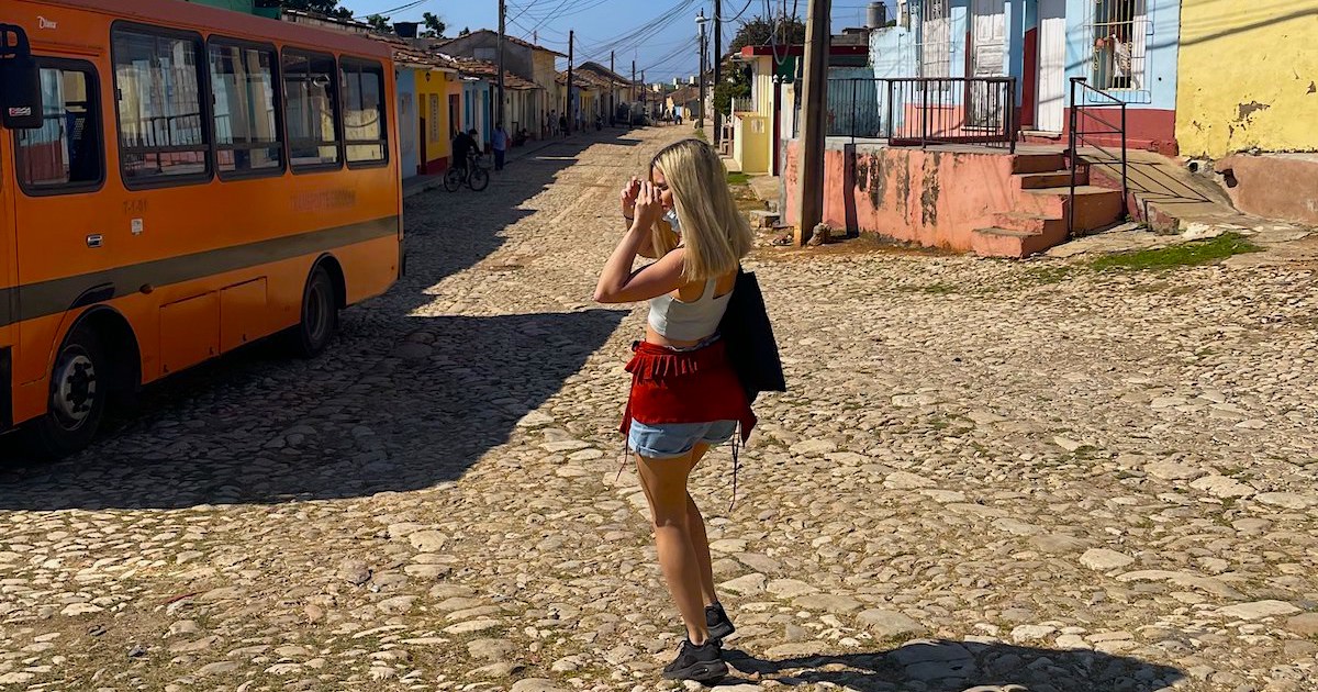 Escape Artist Katie on a cobbled street in Trinidad with colourful houses