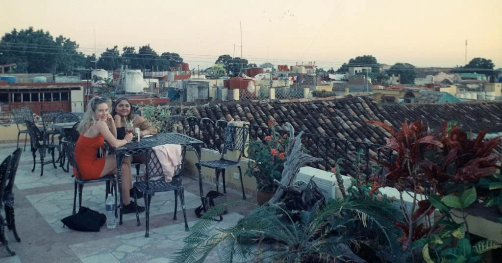 Two girls relax with cocktails on a terrace bar in Trinidad Cuba.