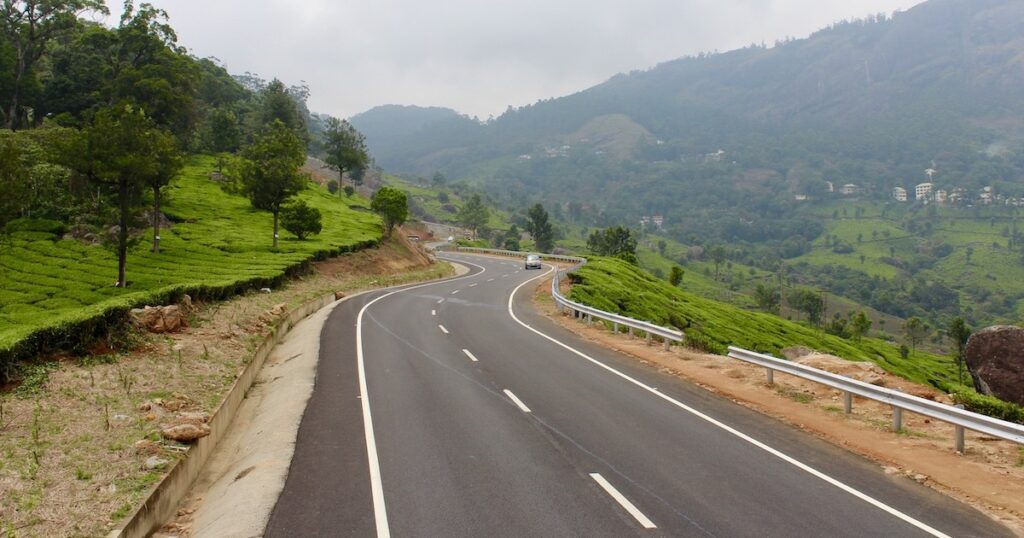 Winding mountain pass surrounded by tea fields in Munnar.