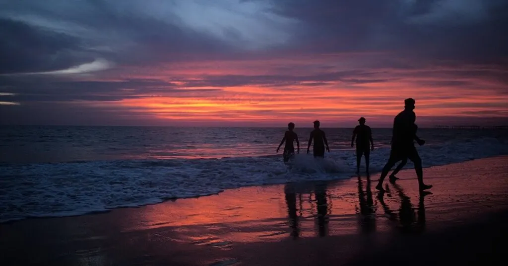 Shadows of a group of locals on Alleppey beach at sunset