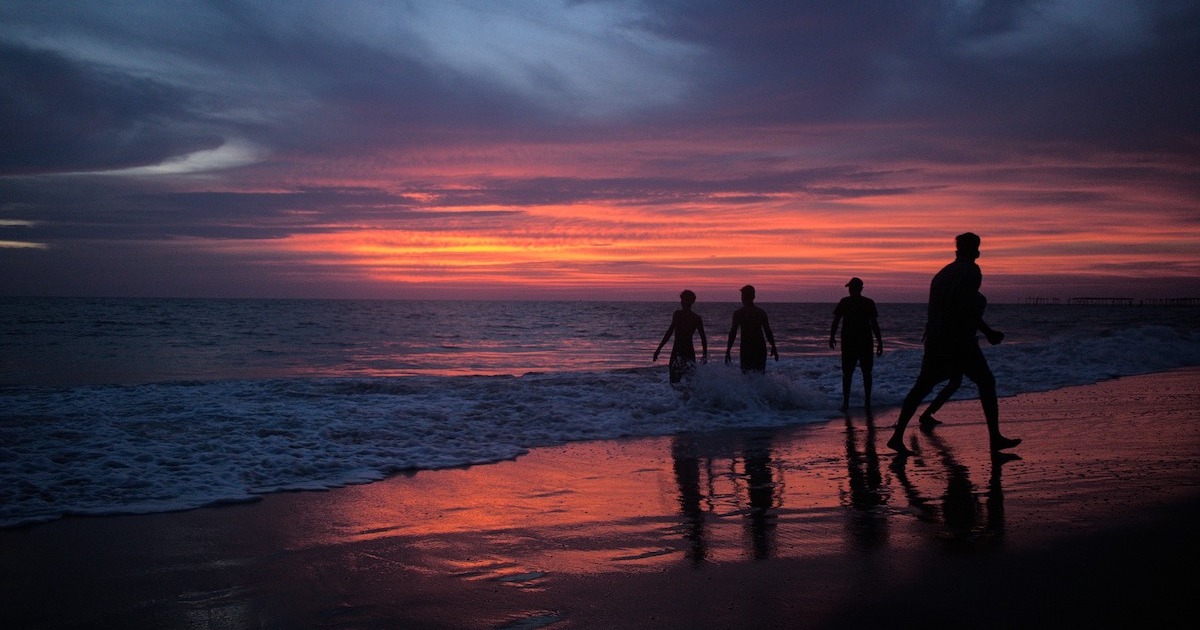 Shadows of a group of locals on Alleppey beach at sunset