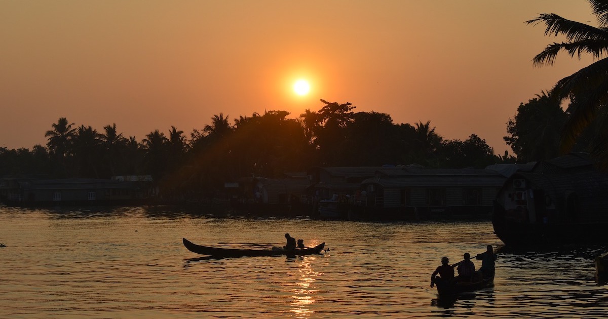 Shikara boat gliding along Alleppey backwaters at sunset