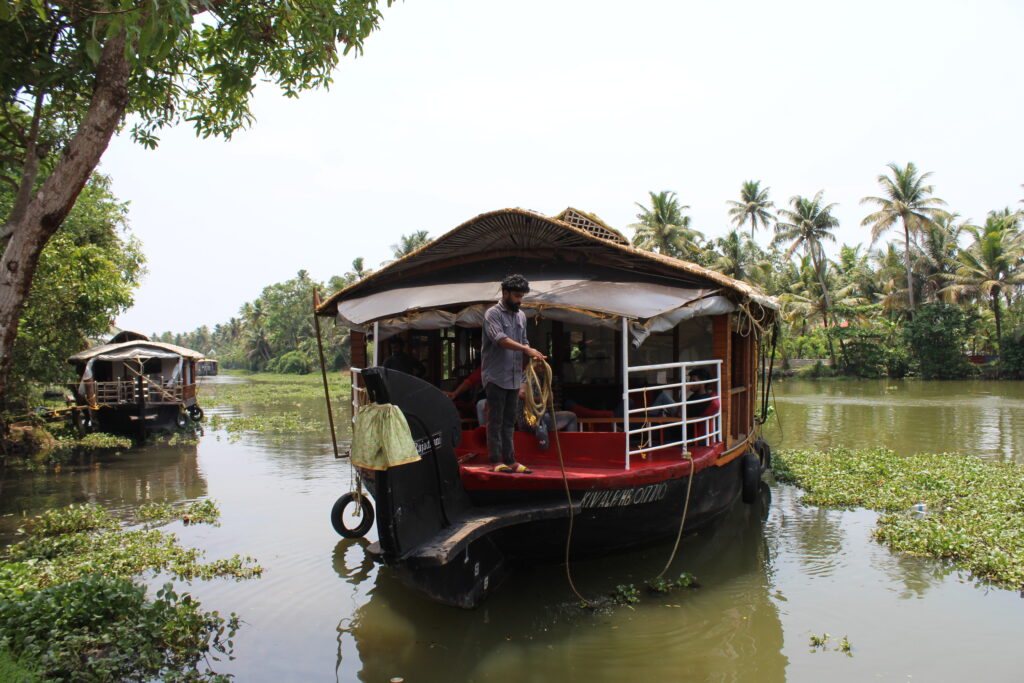 Man stood at the front of a houseboat prepares to throw out a line