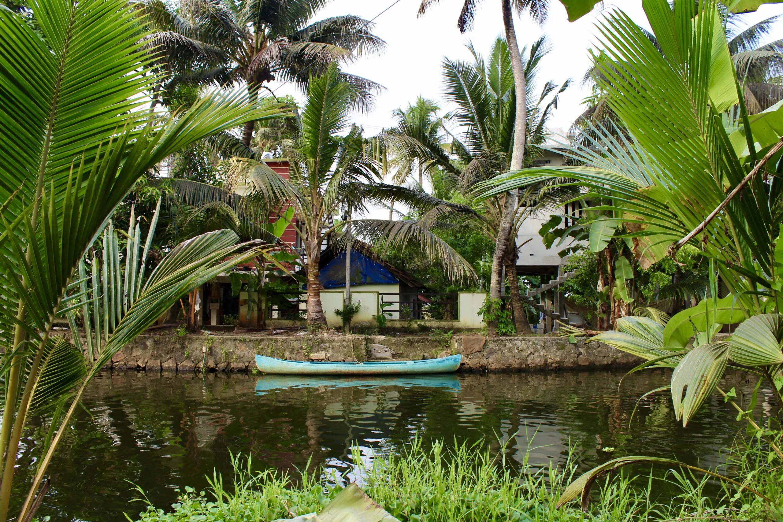 A canoe parked beside a canalside house in a village in Alleppey.
