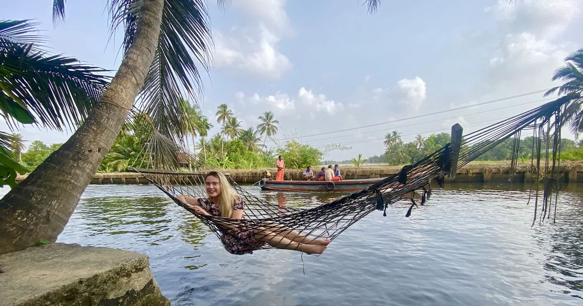 Woman dressed in a knee-length t-shirt dress, swimming in a hammock over Alleppey backwaters