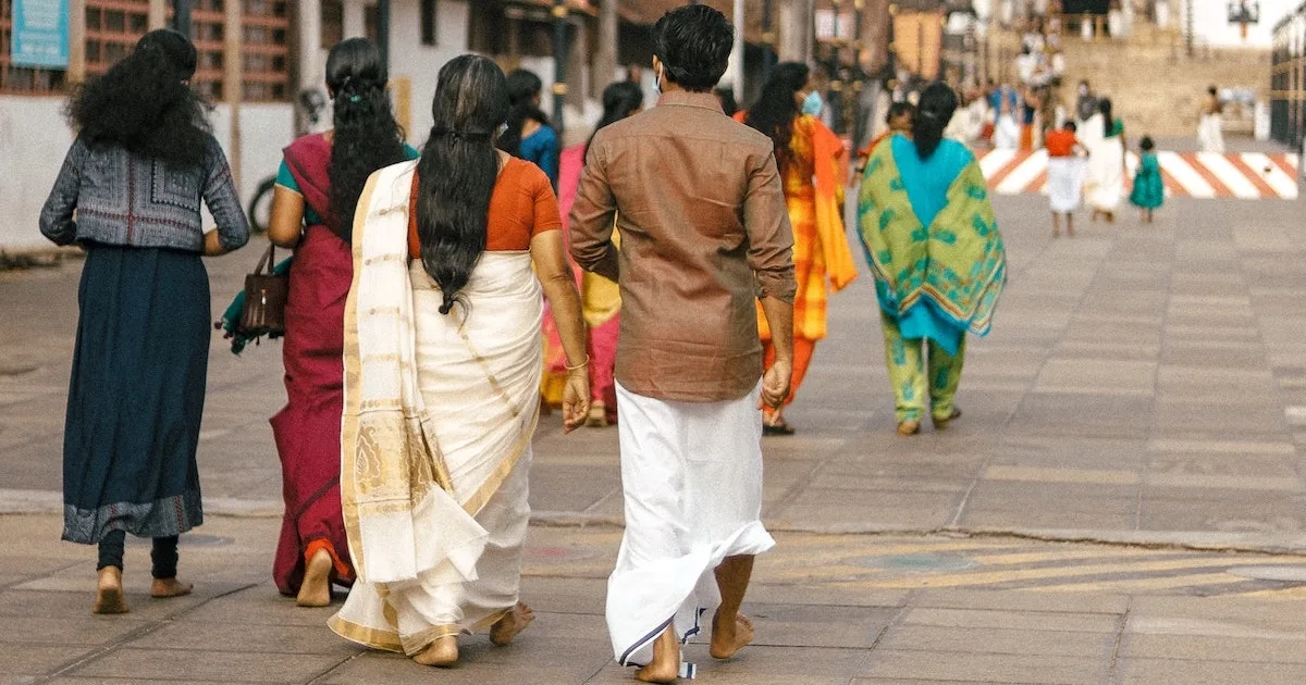 Kerala locals dressed in traditional mundu saree and dhotis enter a temple.