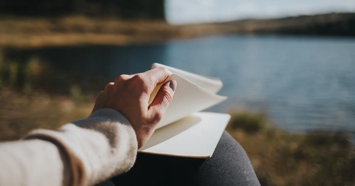 A woman travel journaling and flicking through the pages of a book.