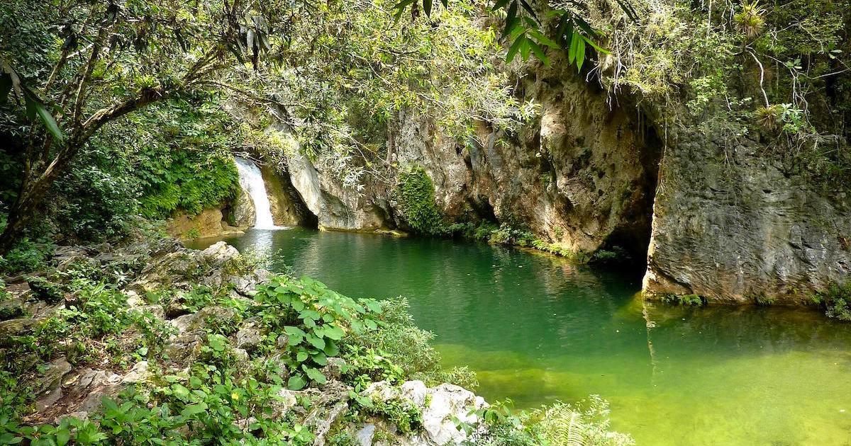 Green and blue swimming hole with a waterfall in Topes de Collantes Natural Park