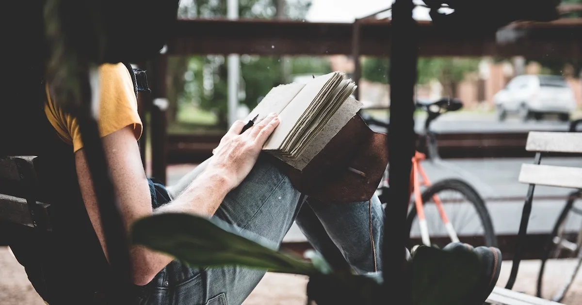 Lady wearing jeans is travel journaling outside of a coffee shop