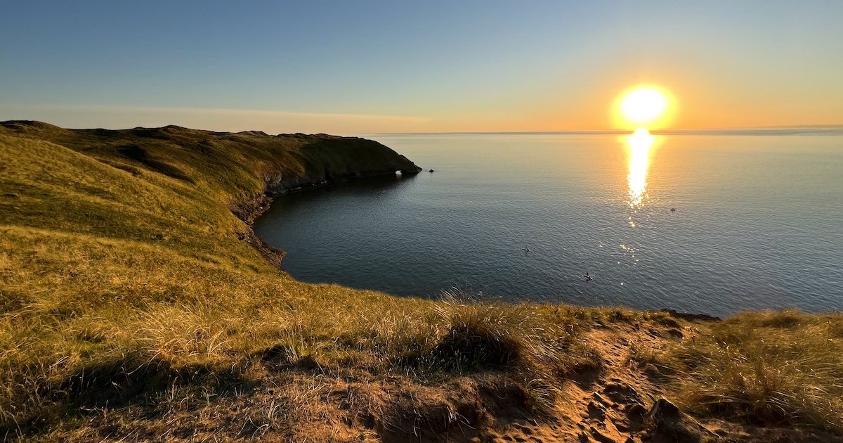 Golden sunset over Blue Pool Bay, including a view of a small rock arch.