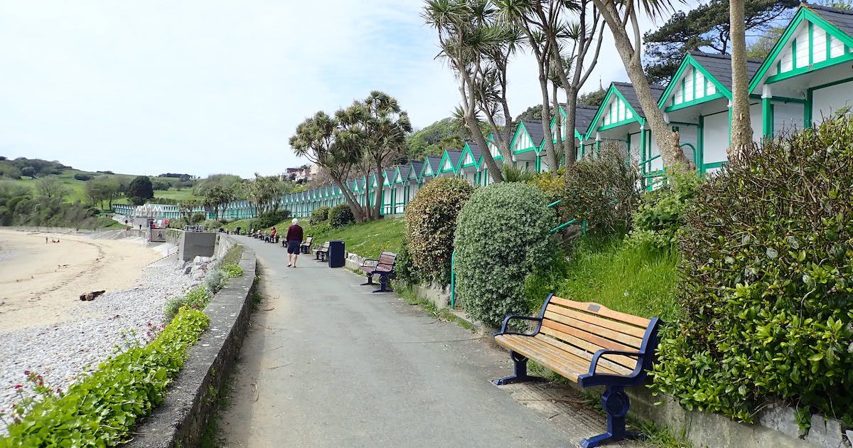 A promenade lined with white beach huts at Langland Bay near The Mumbles