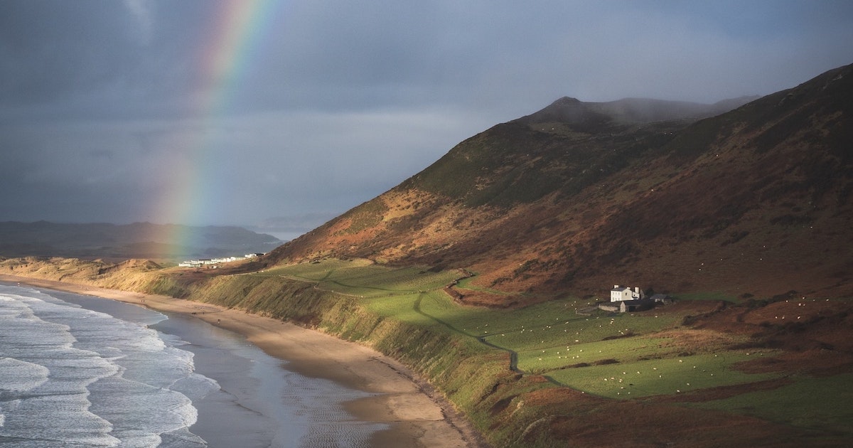 A rainbow forms over the hills above Rhossili Bay in Gower.