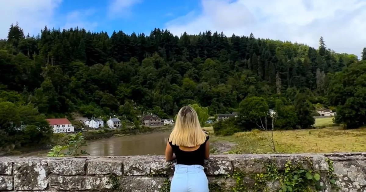 Blonde girl leaning against a bridge in Tintern village over the river Wye.