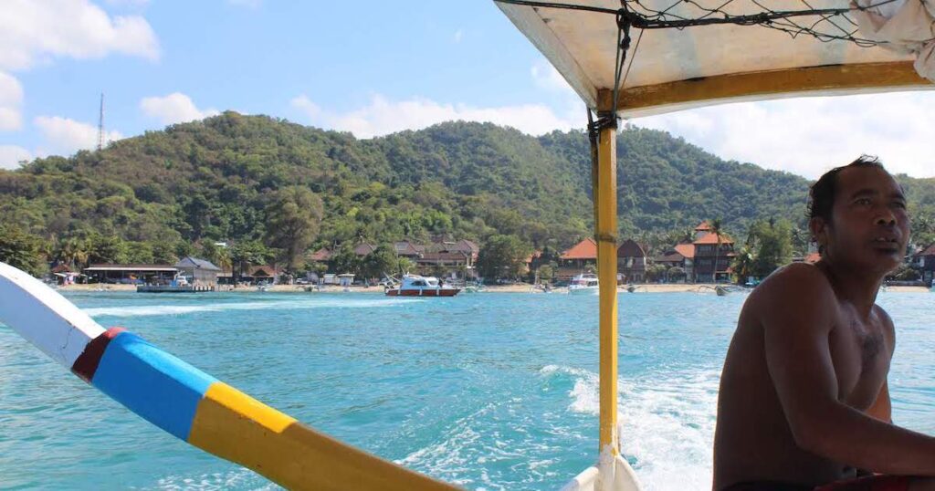 Balinese man drives a Balinese boat away from Padangbai port