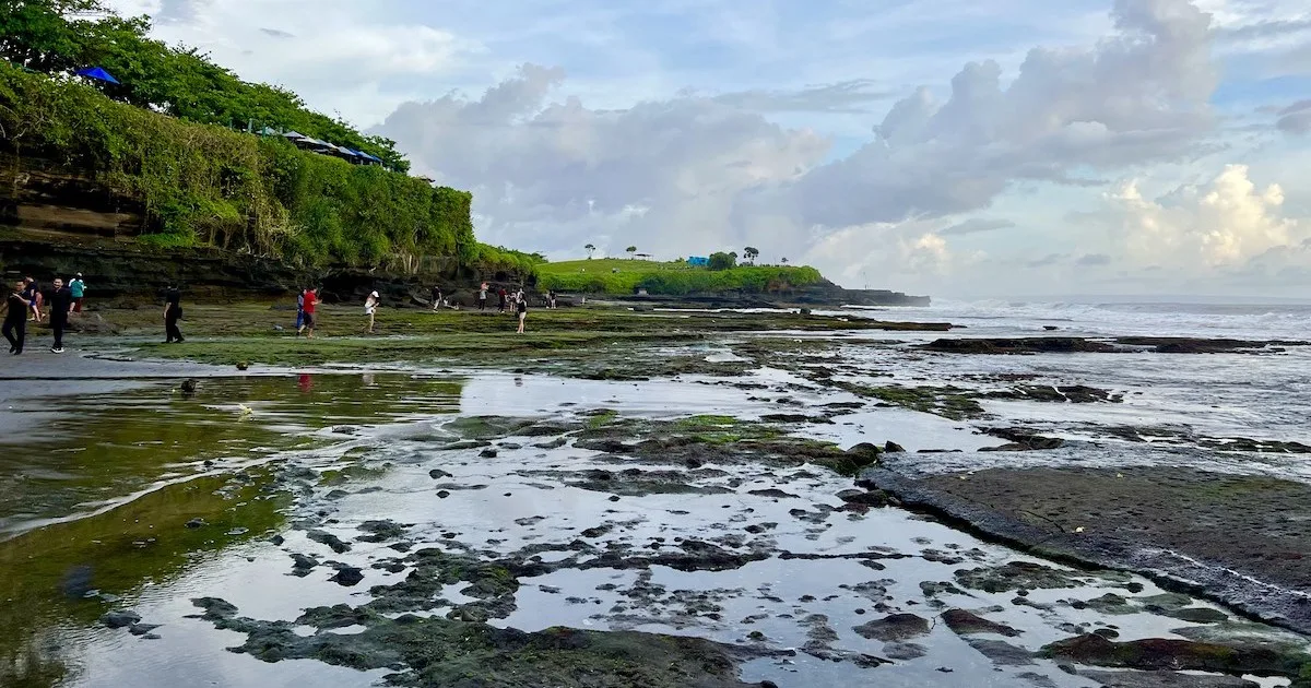 Rocky crevices are filled with seawater on Sunset Beach at the Tanah Lot sunset.