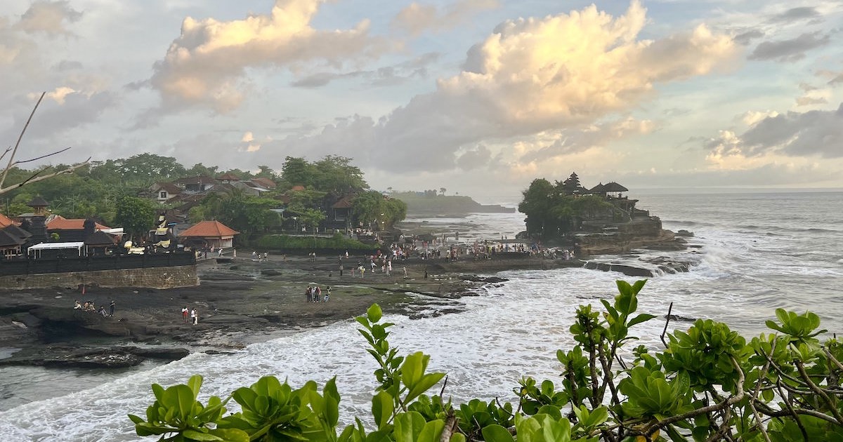 Tanah Lot Temple framed by a golden sunset and a cove with a waterfall.