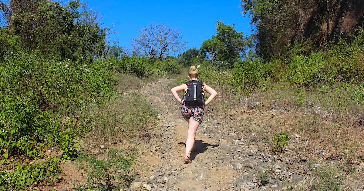 Blonde woman walks uphill on a gravel track in Padangbai