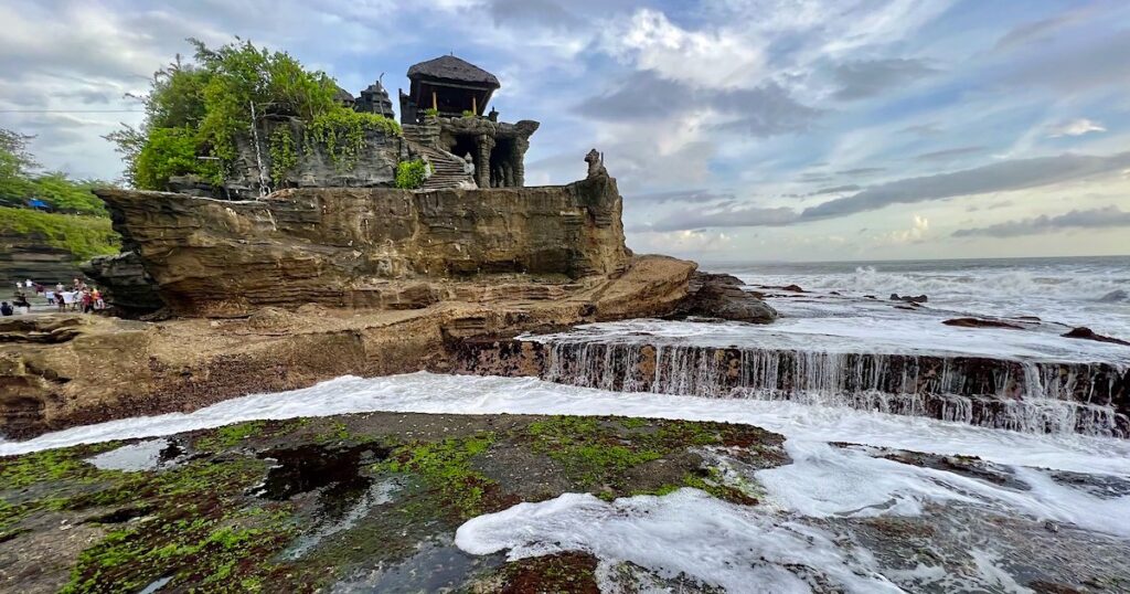 Tanah Lot Temple surrounded by sea water on the rocks.