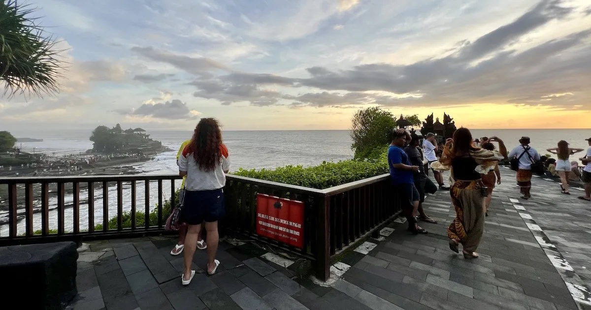 Tourists lean against the railings on the clifftop over Tanah Lot Temple.