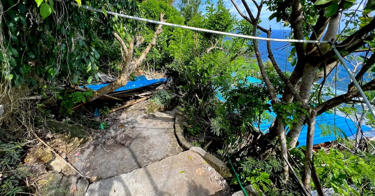 Paved steps lead downhill through the forest next to Nunggalan Beach.