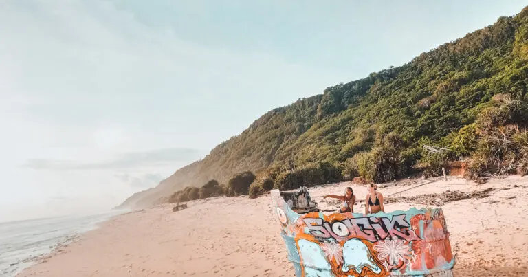 Two girls laugh while posing on the Nunggalan Beach shipwreck.