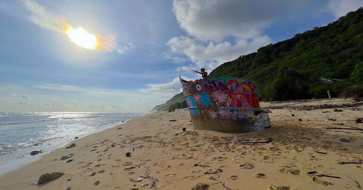 Girl stands on a shipwreck covered in graffiti on Nunggalan Beach.
