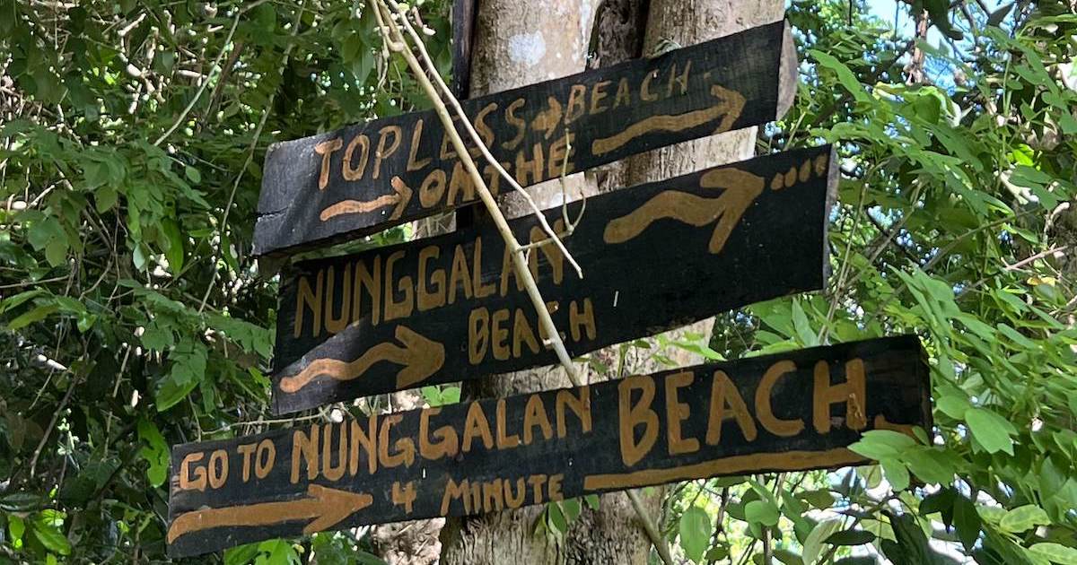 Signposts for Nunggalan Beach and a topless beach in the forest.