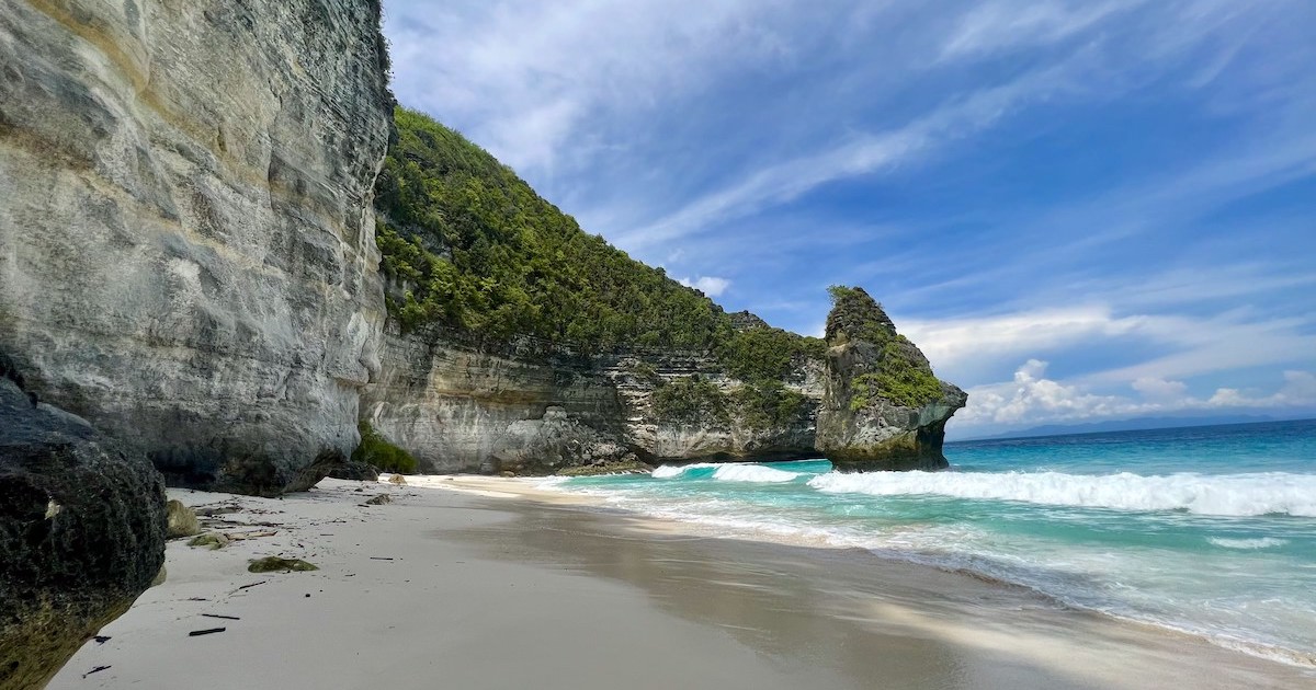 A diamond-shaped rock lies beside a stretch of white sand at Suwehan in Nusa Penida.