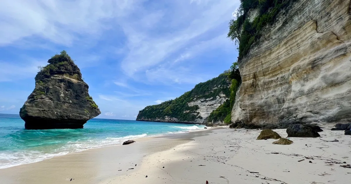 A diamond-shaped rock juts out of shallow ocean alongside Suwehan Beach.