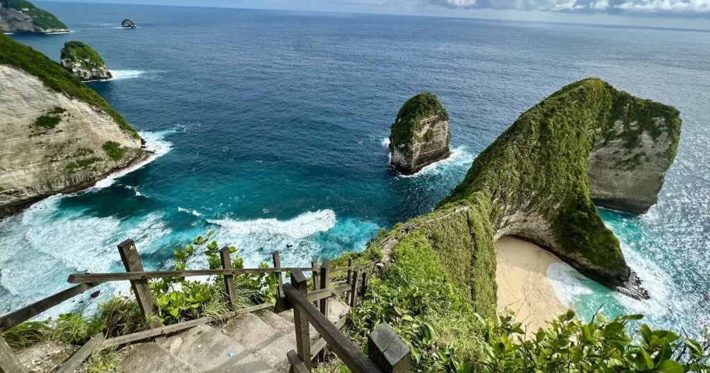 Two beaches on either side of a sheer cliff pathway, including Kelingking Beach on the right.