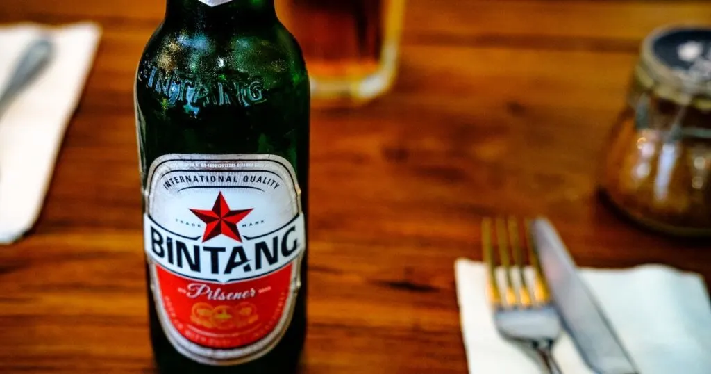 Bintang beer resting on a wooden table.