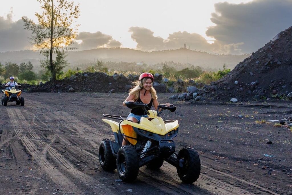 Escape Artist Katie owner riding a yellow quad bike over former lava fields on Mount Mayon in the Philippines.