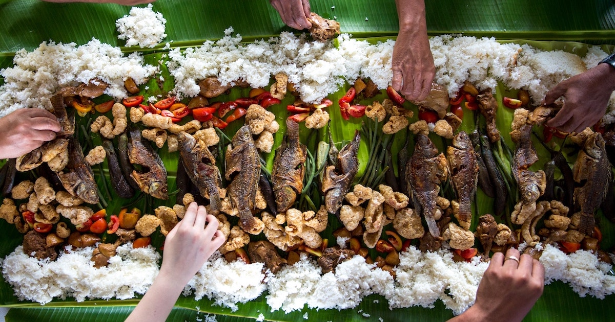 Hands reach to pick food from a fiesta in the Philippines.