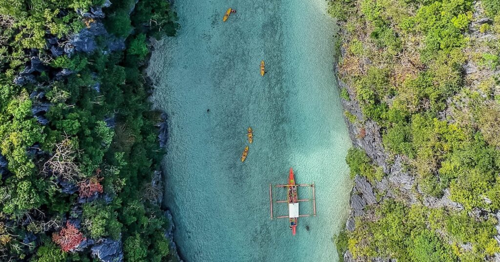 Aerial view of a bangka boat and kayaks on clear water in Palawan.
