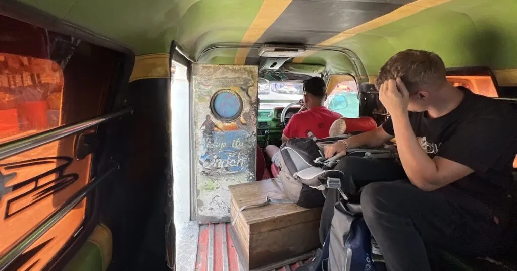 Tourist sits sideaways in a cramped bus in Lake Toba.