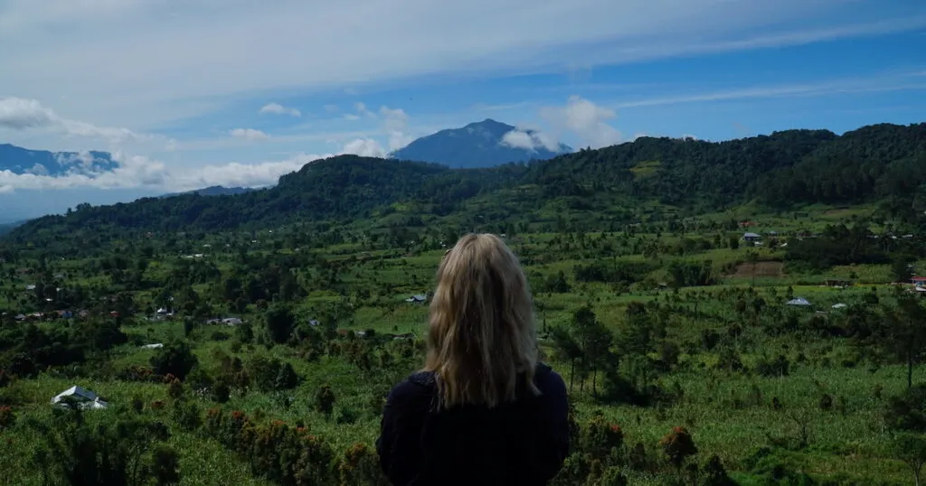 Woman gazes at a volcano over countryside in Sumatra.