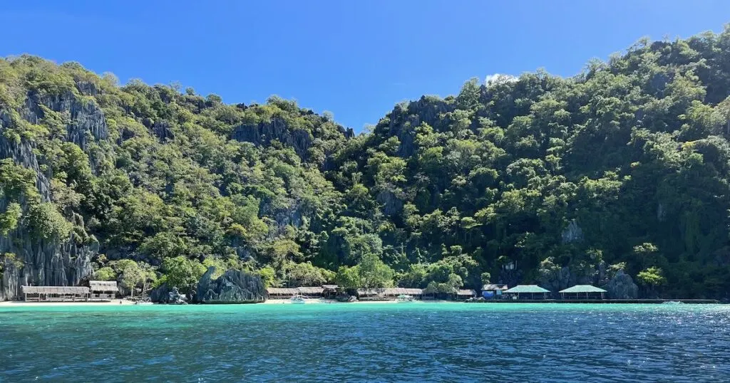 Wooden huts line Banul Beach, a remote beach popular for island hopping in Coron.