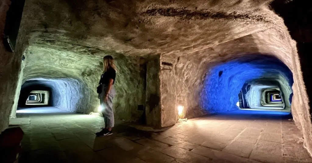 Woman stands at the intersection of two tunnels in the Japanese Caves in Bukittinggi.