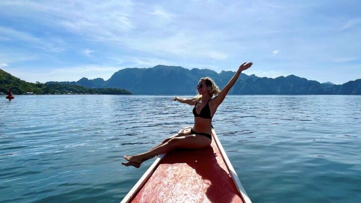 Girl wearing a bikini sits on the edge of a bangka boat while island hopping in Coron.