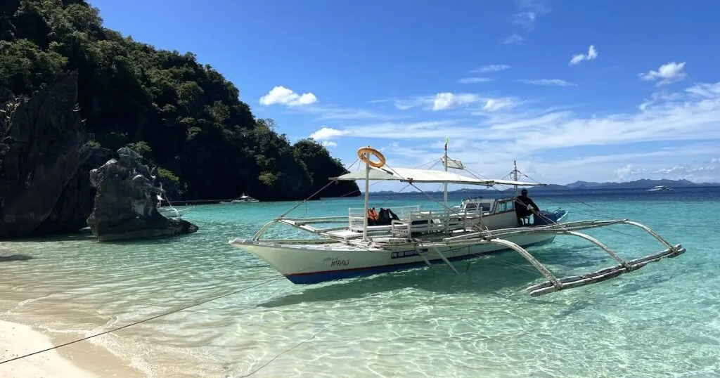Bangka boat used for Coron island hopping tours is parked in the shallows at Banul Beach.