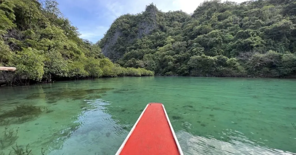 Red tip of a bangka boat sails through the shallows of Twin Lagoon in Coron.