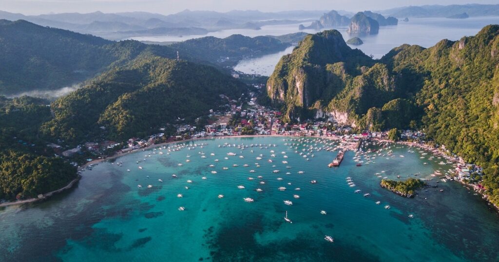 Aerial view of Bacuit Bay in El Nido, lined with boats and houses.