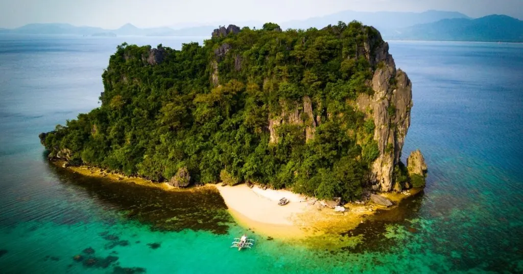 A limestone island with a white-sand beach and tall cliffs.
