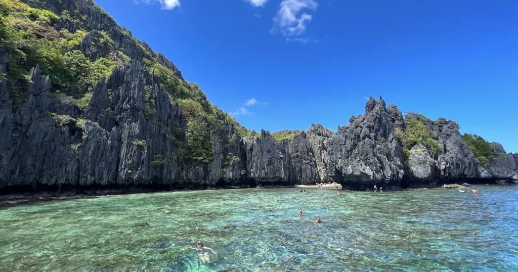 White-sand Hidden Beach partially concealed behind jagged limestone cliffs, a stop on the best El Nido tour.