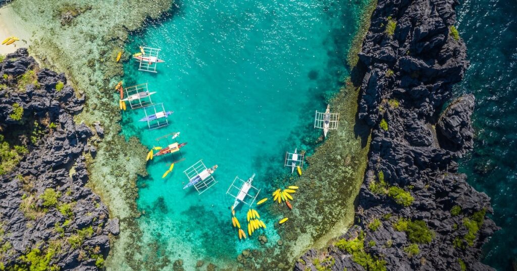 Aerial view of bangka boats and yellow kayaks in Small Lagoon in El Nido.