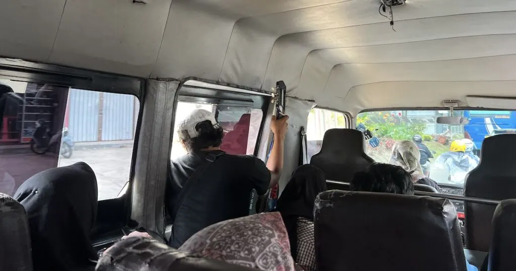 Man with a guitar sits on a local bus from Bukittinggi to Harau Valley in Sumatra.