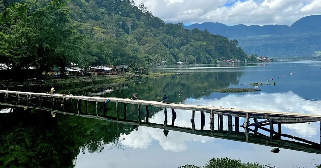 Fishermen sitting on a wooden pier on the west shore of Maninjau Lake.