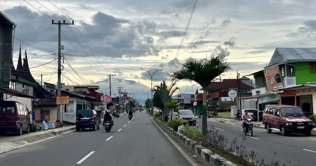 The main highway between Harau and Payakumbuh with cars and scooters, plus distant mountains.
